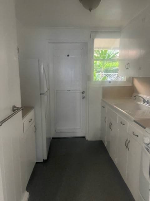 a white kitchen with a white refrigerator and sink